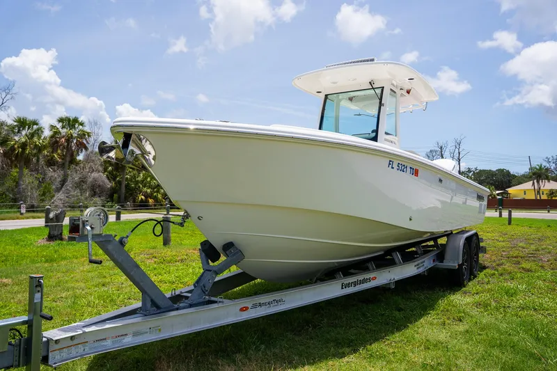  Yacht Photos Pics 2021 Everglades 273 Center Console boat on trailer, parked on grass under blue sky.