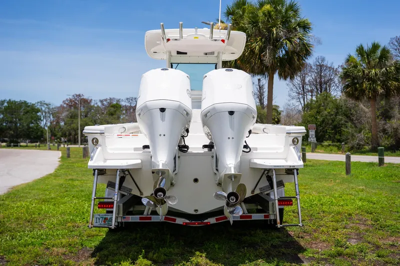  Yacht Photos Pics 2021 Everglades 273 Center Console boat with dual outboard motors, parked on grass.
