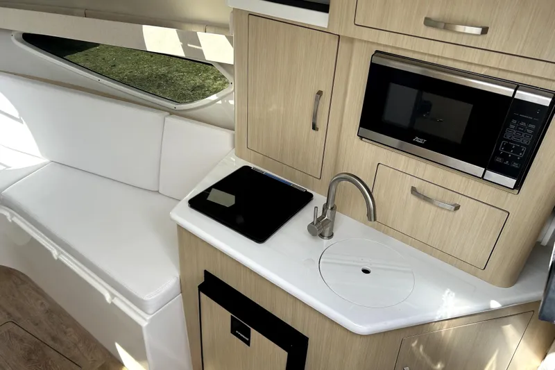  Yacht Photos Pics 2023 Regal 28 Express boat interior with kitchenette, microwave, and seating area.