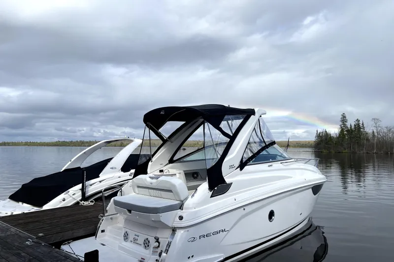  Yacht Photos Pics 2023 Regal 28 Express boat docked on a serene lake with a rainbow in the background.