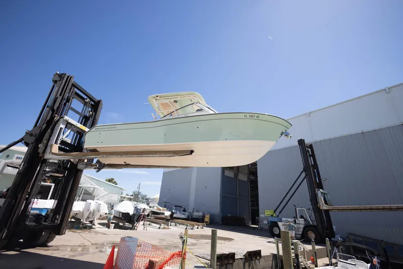  Yacht Photos Pics 2021 Grady-White Freedom 275 boat lifted by forklift in marina setting.