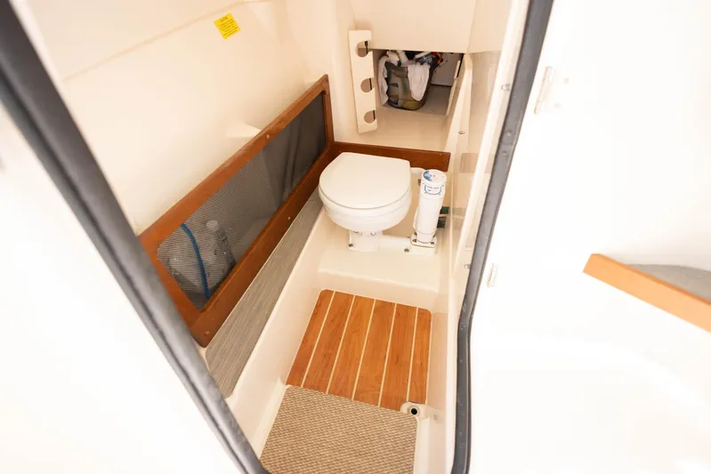  Yacht Photos Pics 2021 Grady-White Freedom 275 boat interior with compact marine toilet and wooden flooring.