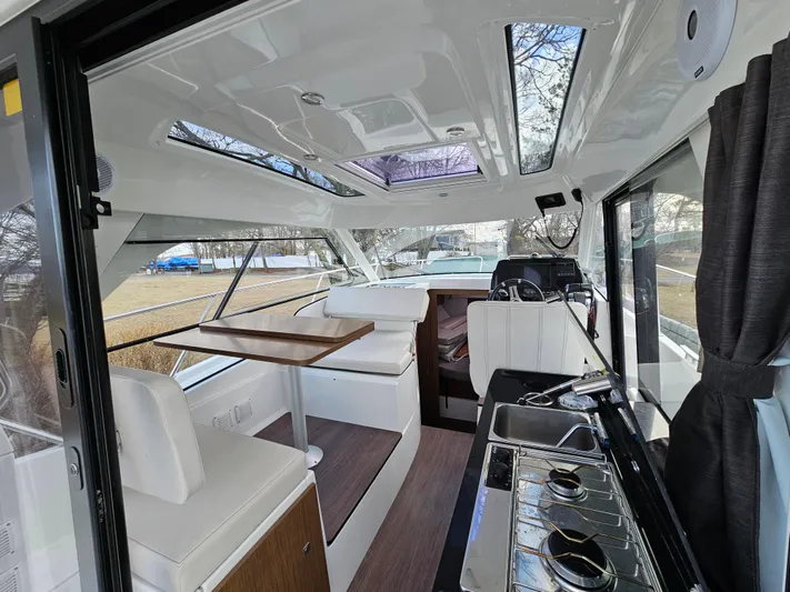  Yacht Photos Pics Interior of 2020 Beneteau Antares 9 boat with seating, table, and kitchenette.