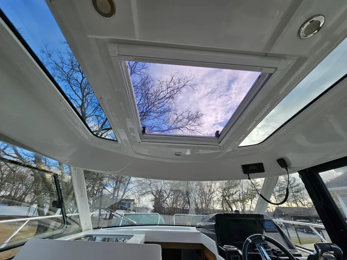  Yacht Photos Pics Interior view of 2020 Beneteau Antares 9 boat with open sunroof and clear sky.