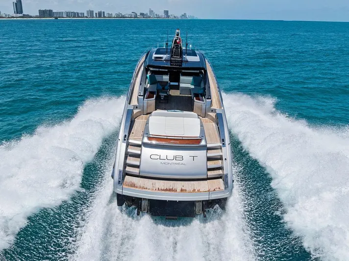 Club T Yacht Photos Pics 2023 Riva 68 Diable yacht cruising on open sea, city skyline in background.