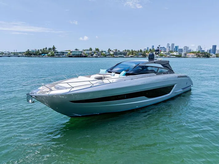 Club T Yacht Photos Pics 2023 Riva 68 Diable yacht cruising on clear blue water near a city skyline.