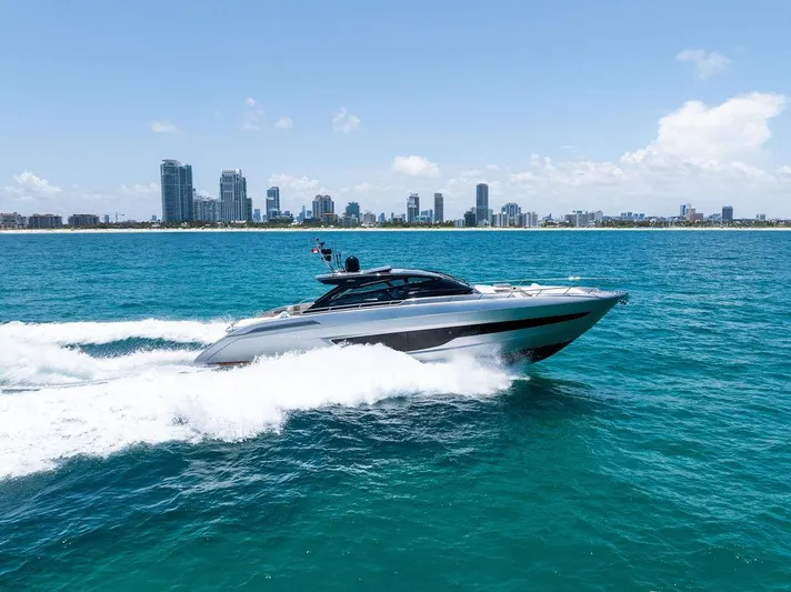 Club T Yacht Photos Pics 2023 Riva 68 Diable yacht cruising on blue ocean with city skyline in background.