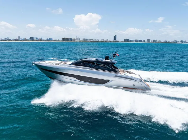 Club T Yacht Photos Pics 2023 Riva 68 Diable yacht cruising on open sea with city skyline in background.