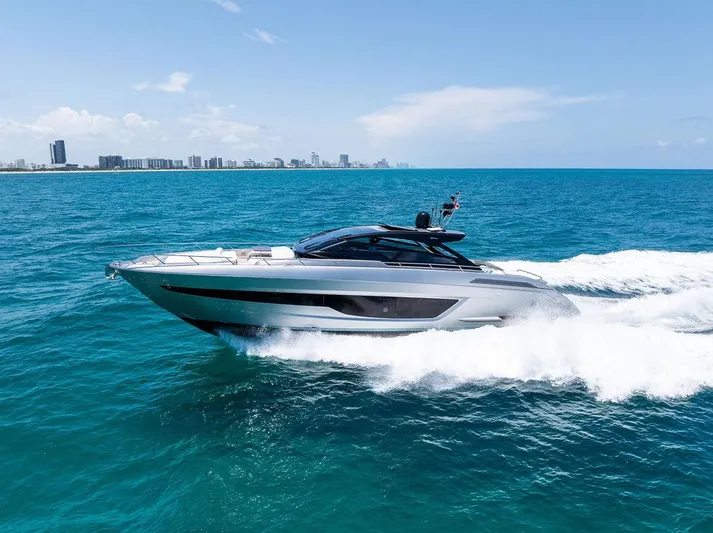 Club T Yacht Photos Pics 2023 Riva 68 Diable yacht cruising on blue ocean near city skyline.