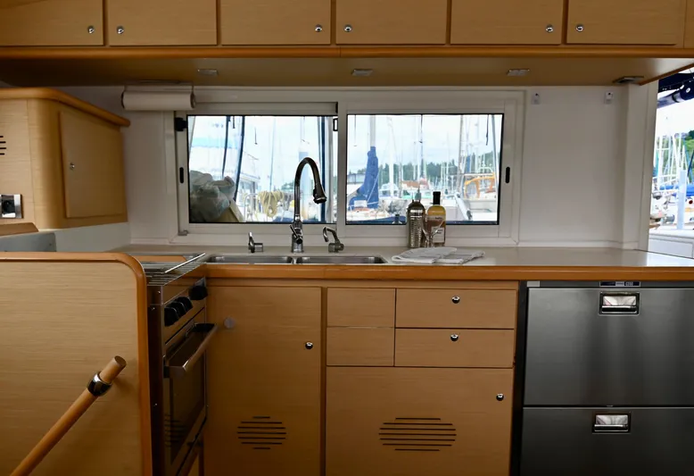  Yacht Photos Pics Interior of 2009 Lagoon 440 yacht kitchen with wooden cabinets and marina view.