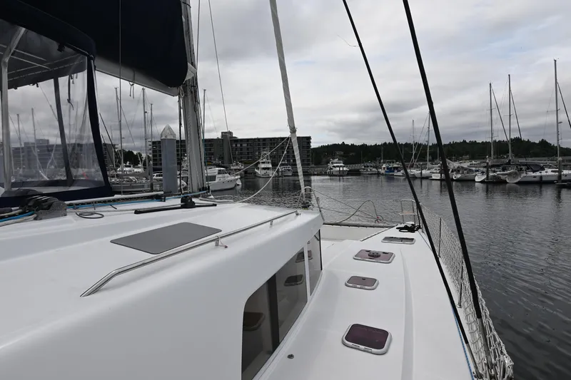  Yacht Photos Pics 2009 Lagoon 440 catamaran docked in a marina with sailboats and cloudy sky.