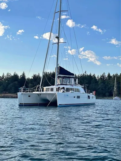  Yacht Photos Pics 2009 Lagoon 440 catamaran sailing on calm waters with forested shoreline in the background.