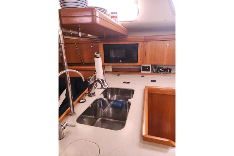 Seaquel Yacht Photos Pics 2003 Hunter 386 yacht kitchen with sink, microwave, and wooden cabinetry.