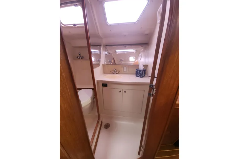 Seaquel Yacht Photos Pics 2003 Hunter 386 yacht bathroom with sink, mirror, and wooden cabinetry.