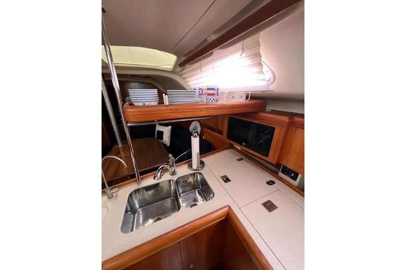 Seaquel Yacht Photos Pics Interior of 2003 Hunter 386 yacht kitchen with sink, microwave, and wooden cabinetry.
