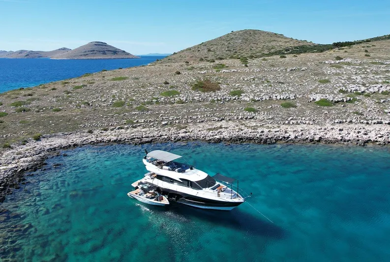  Yacht Photos Pics Sunseeker Manhattan 66 yacht anchored in a serene, clear blue bay, 2017 model.