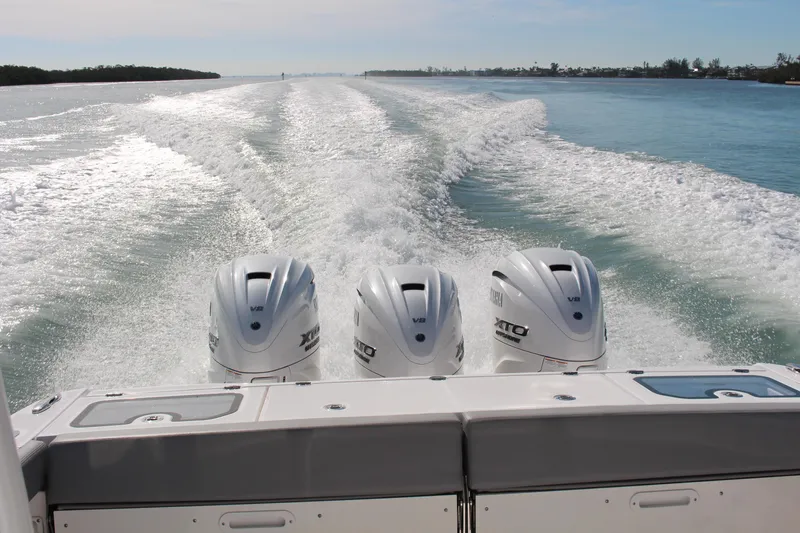  Yacht Photos Pics 2024 Everglades 395 Center Console boat with triple outboard engines on open water.