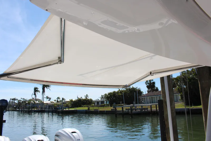  Yacht Photos Pics 2024 Everglades 395 Center Console boat with canopy, docked by a scenic waterfront.