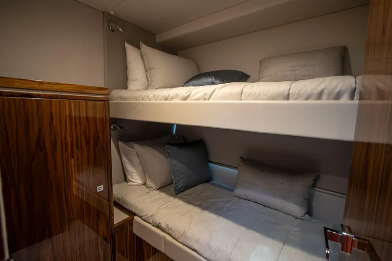  Yacht Photos Pics Luxurious 2024 Riviera 4600 SY yacht cabin with cozy bunk beds and elegant wood finish.