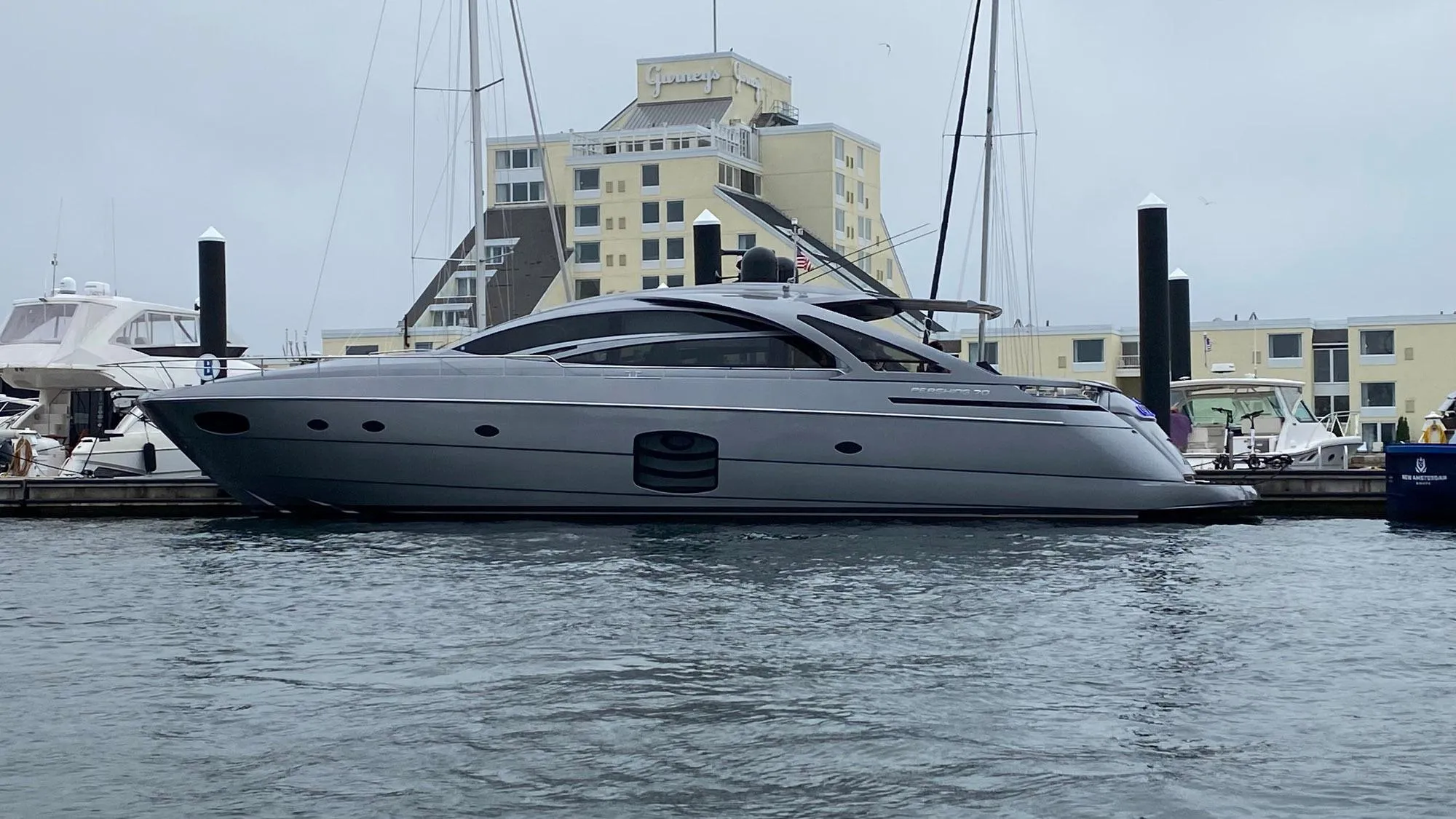 2016 Pershing 70 yacht docked at marina with modern architecture in background.