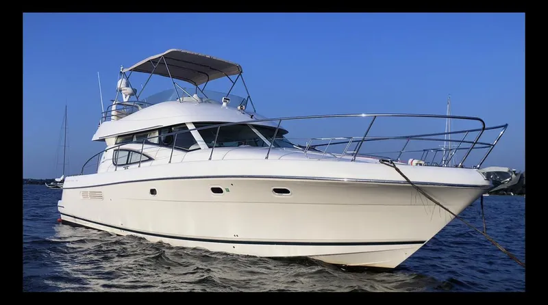 Our Three Buoys Yacht Photos Pics 2007 Jeanneau Prestige 46 yacht on calm water, clear blue sky background.