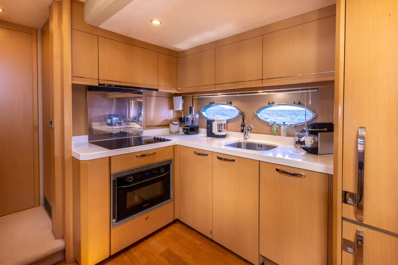 P'tite Bouille Yacht Photos Pics Luxurious kitchen interior of 2008 Princess V70 yacht with modern appliances and wooden cabinetry.