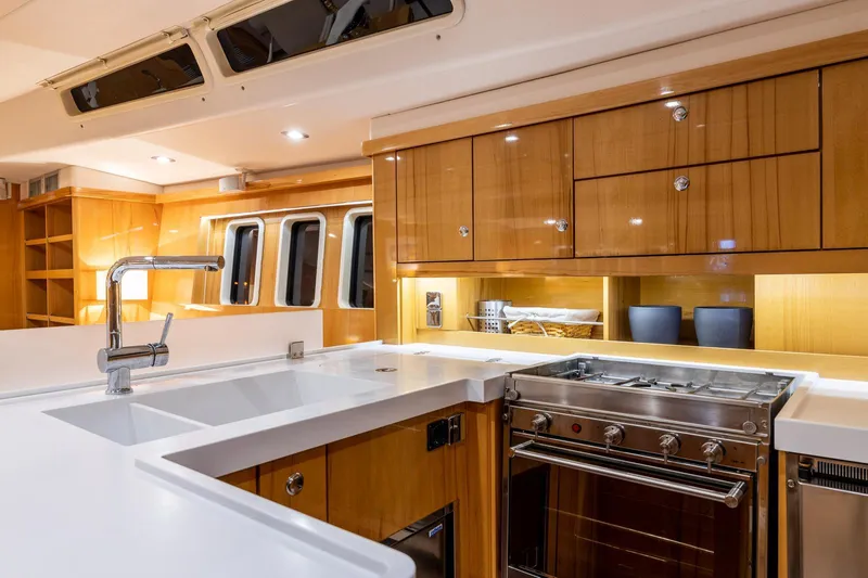  Yacht Photos Pics Luxurious kitchen interior of 2013 Hanse 630e yacht with modern appliances and wooden cabinetry.