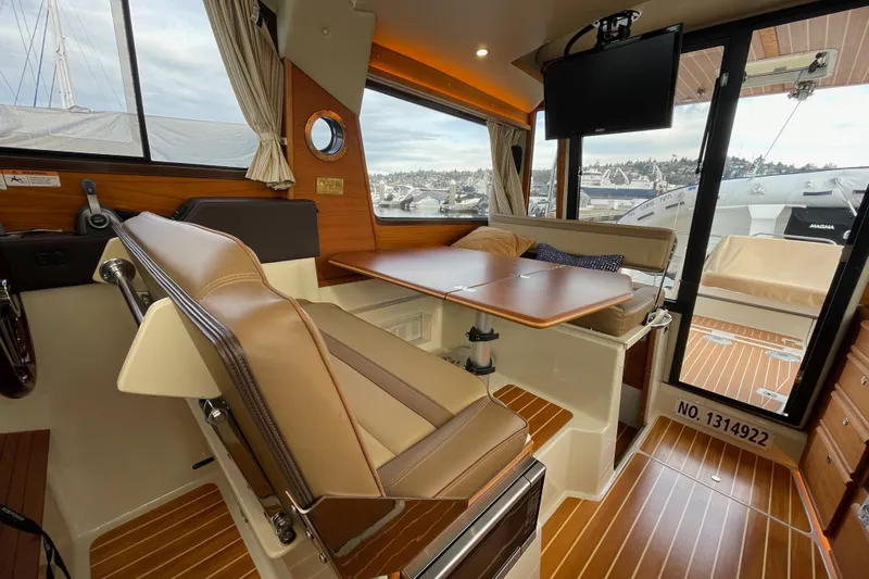 Poseidon&rsquo;s Lanai Yacht Photos Pics 2021 Ranger Tugs R-29 CB interior with seating, table, and TV, showcasing elegant wood finishes.