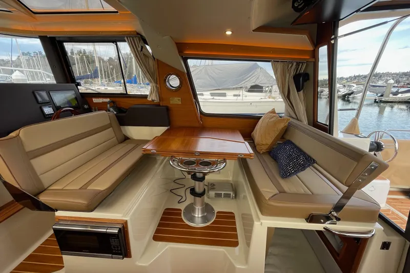 Poseidon&rsquo;s Lanai Yacht Photos Pics Interior of 2021 Ranger Tugs R-29 CB with elegant seating and wooden table.