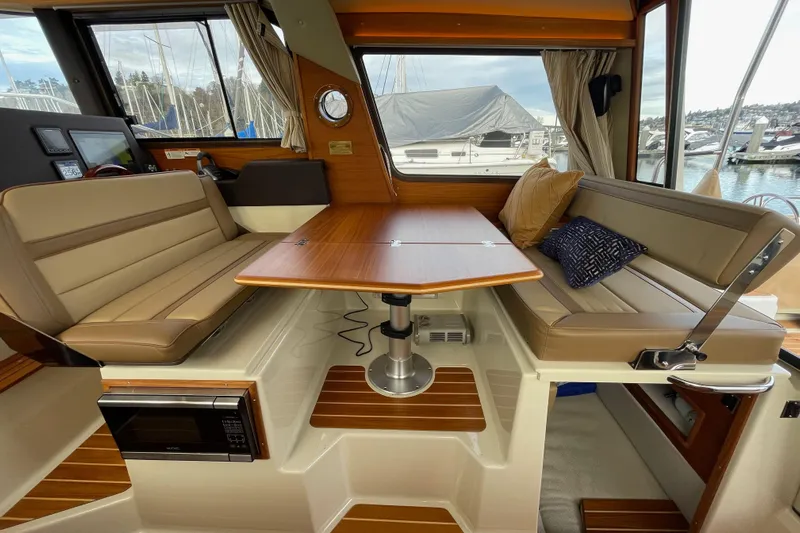 Poseidon&rsquo;s Lanai Yacht Photos Pics 2021 Ranger Tugs R-29 CB interior with dining area, wood table, and cushioned seating.