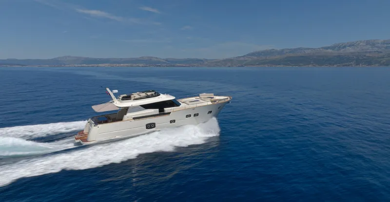 Monachus 70 Fly Yacht Photos Pics 2026 Monachus 70 Fly yacht cruising on open sea with scenic mountain backdrop.