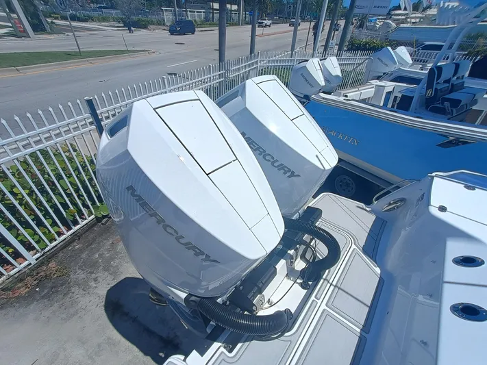 302-126 Yacht Photos Pics 2025 Blackfin 302 DC boat with dual Mercury outboard engines, docked near a fence.
