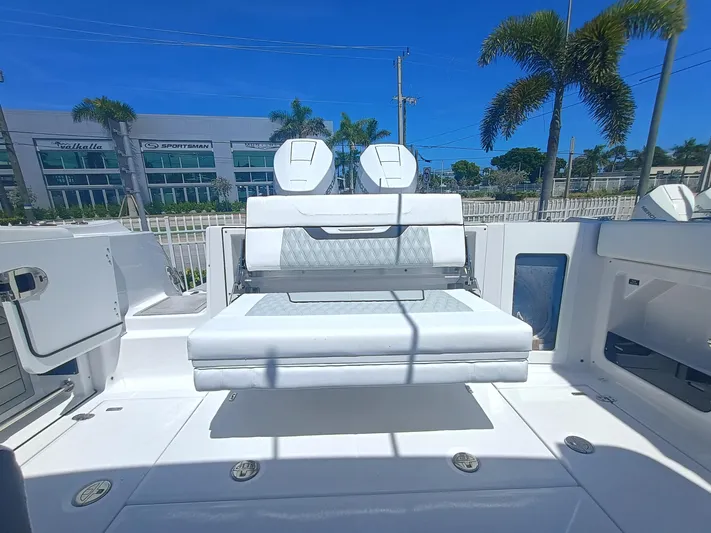 302-126 Yacht Photos Pics 2025 Blackfin 302 DC boat interior with white seating, palm trees, and dealership in background.