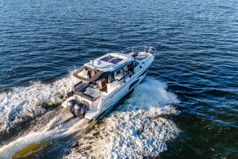 Bella Thalassa Yacht Photos Pics 2021 Jeanneau NC 1095 motorboat cruising on open water, rear view.