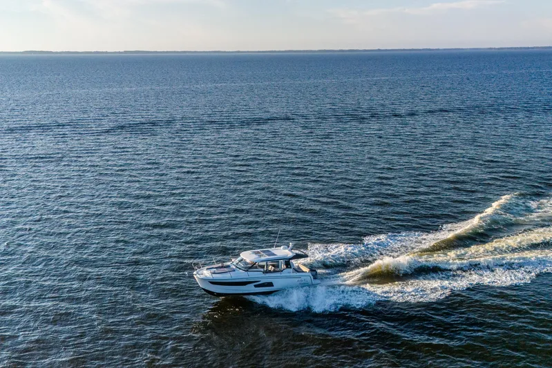 Bella Thalassa Yacht Photos Pics 2021 Jeanneau NC 1095 cruising on open water, creating a wake under clear skies.