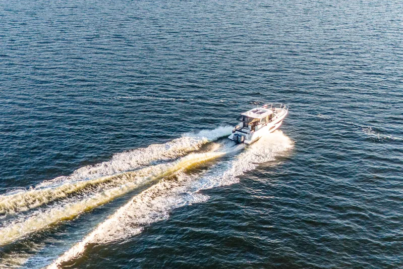Bella Thalassa Yacht Photos Pics 2021 Jeanneau NC 1095 cruising on open water, leaving a wake behind.