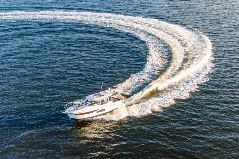 Bella Thalassa Yacht Photos Pics 2021 Jeanneau NC 1095 cruising on open water, creating a dynamic wake pattern.