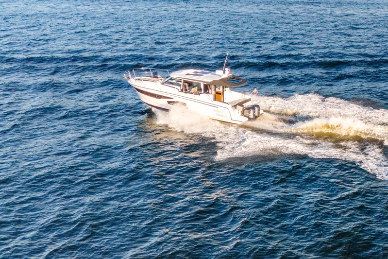 Bella Thalassa Yacht Photos Pics 2021 Jeanneau NC 1095 cruising on open water, creating a wake.