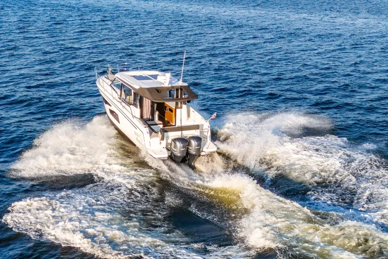 Bella Thalassa Yacht Photos Pics 2021 Jeanneau NC 1095 cruising on open water, creating a dynamic wake.