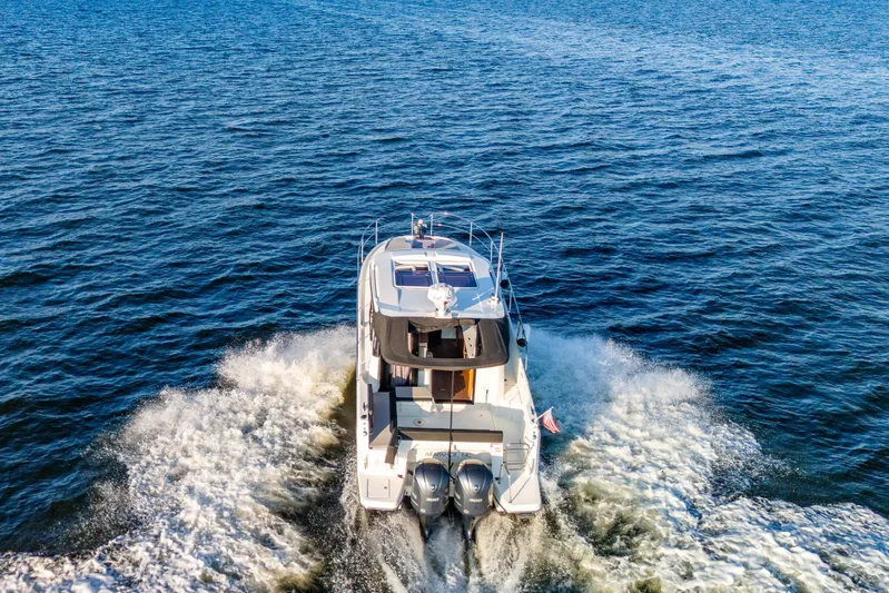 Bella Thalassa Yacht Photos Pics 2021 Jeanneau NC 1095 cruising on open water, rear view with twin engines.