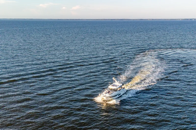 Bella Thalassa Yacht Photos Pics 2021 Jeanneau NC 1095 cruising on open water, leaving a wake behind.