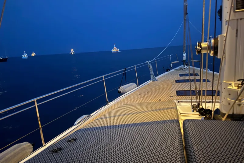  Yacht Photos Pics Jeanneau 64 yacht deck at dusk, 2016 model, with distant boats on calm sea.