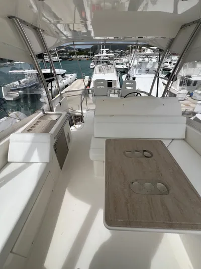 New Listing Yacht Photos Pics 2016 Riviera 45 Open Flybridge yacht interior with seating and table, docked at marina.