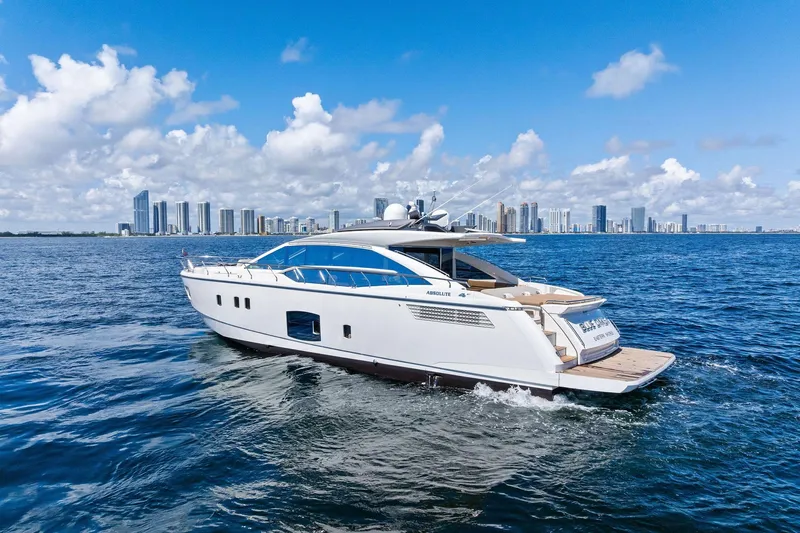 Blue Daksa Yacht Photos Pics Luxurious 2013 Absolute 64 yacht cruising near a city skyline under a clear blue sky.