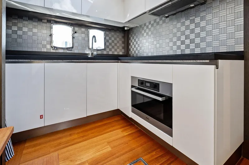 Blue Daksa Yacht Photos Pics Modern yacht kitchen with sleek white cabinets, wood flooring, and stylish backsplash. Absolute 64, 2013 model.