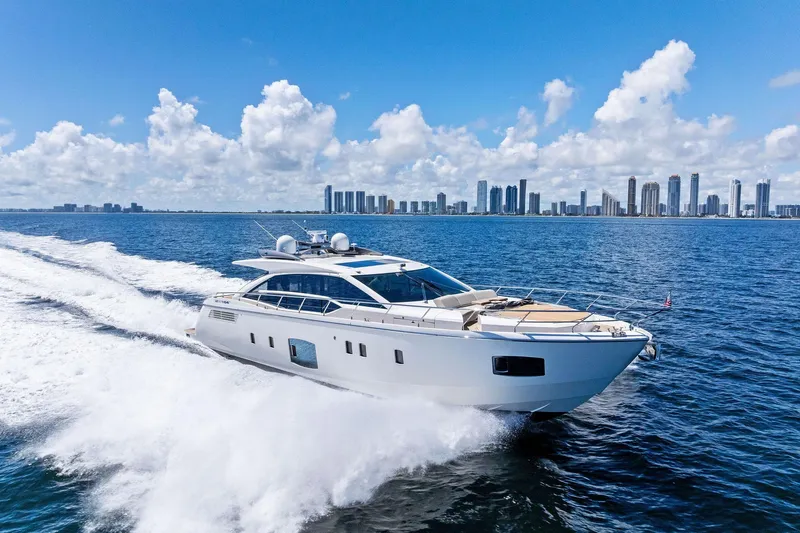 Blue Daksa Yacht Photos Pics Luxurious 2013 Absolute 64 yacht cruising on blue ocean with city skyline backdrop.