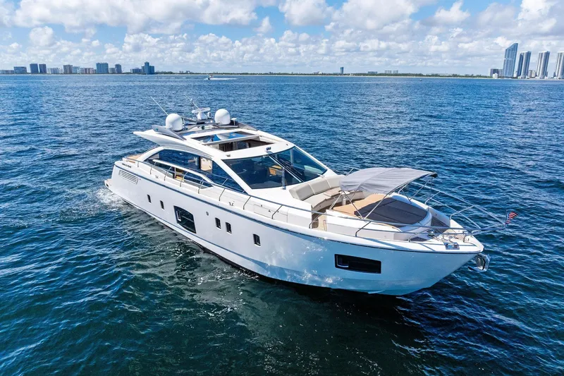 Blue Daksa Yacht Photos Pics Luxurious 2013 Absolute 64 yacht cruising on open water with city skyline backdrop.