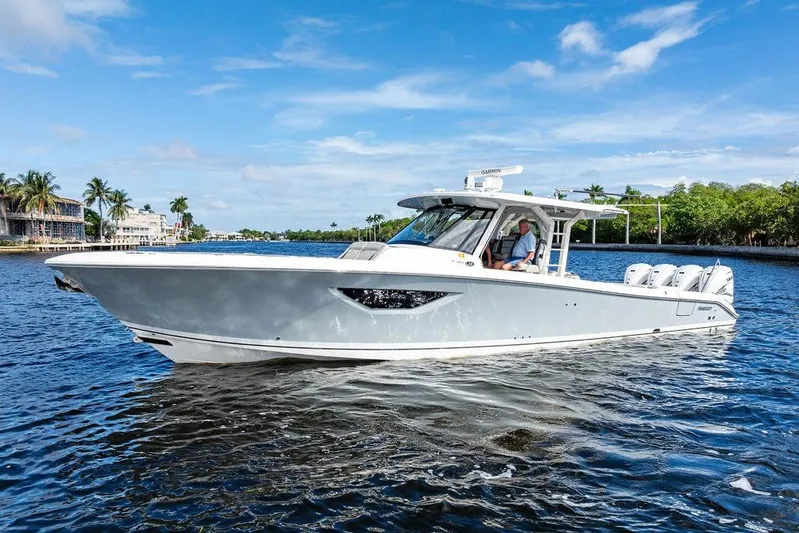No Vacancy Yacht Photos Pics 2022 Pursuit S 428 Sport boat cruising on a sunny day, surrounded by water and palm trees.