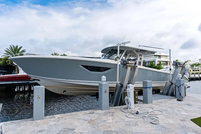 No Vacancy Yacht Photos Pics 2022 Pursuit S 428 Sport boat on lift at marina, under cloudy sky.