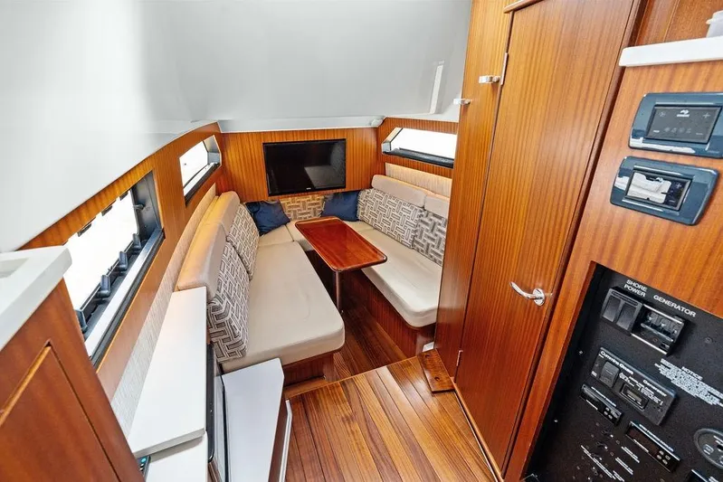No Vacancy Yacht Photos Pics Luxurious interior of 2022 Pursuit S 428 Sport boat with wood paneling and seating area.